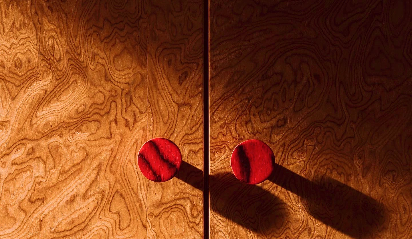 Sculptural red ATHAR knobs on warm wood